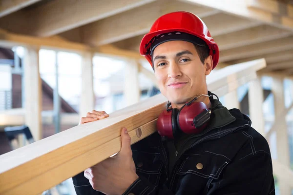 Ahşap inşaat sahasında omzunda taşıyan bir marangoz — Stok fotoğraf