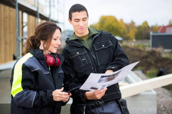 Manliga och kvinnliga snickare diskuterar om Plan — Stockfoto