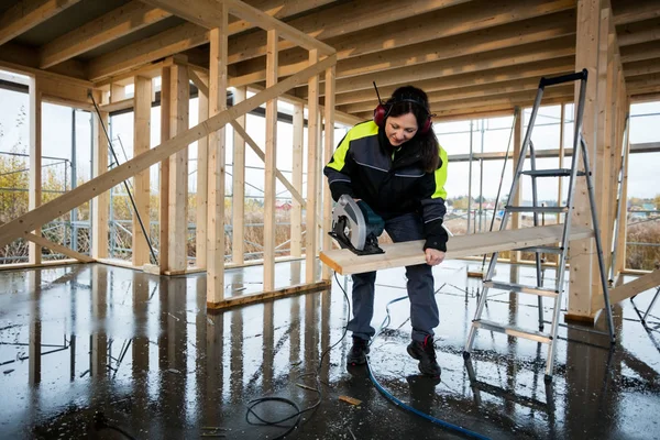 Řezání dřeva s elektrickým ženské Carpenter viděl ve stavebnictví — Stock fotografie
