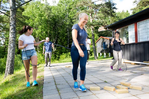 Friends Carrying Ropes While Walking Towards Wooden Blocks On Pa — Stock Photo, Image