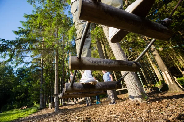 Joven cruzando el puente de troncos en el bosque — Foto de Stock