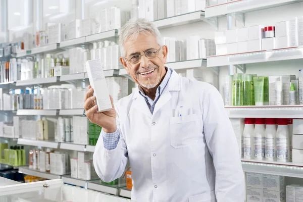 Впевнений фармацевт тримає коробку медицини в аптеці — стокове фото