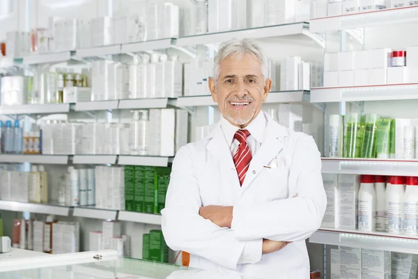 Farmacêutico com braços cruzados em pé na farmácia — Fotografia de Stock