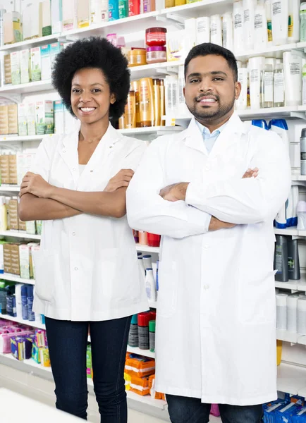 Mannelijke en vrouwelijke apothekers permanent gekruiste armen — Stockfoto