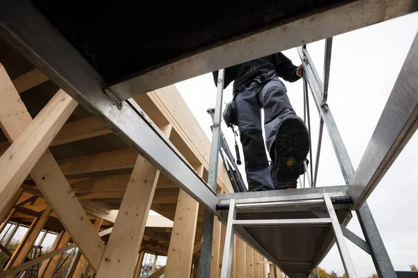 Male Carpenter Moving Down Ladder At Incomplete Building — Stock Photo, Image