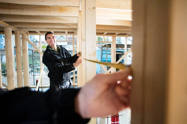 Glada snickaren mäta trä med hjälp av kollega på plats — Stockfoto