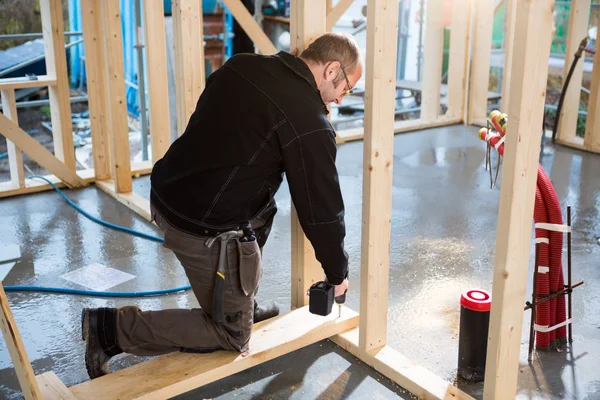 Carpenter Drilling Wood While Kneeling At Construction Site — Stock Photo, Image