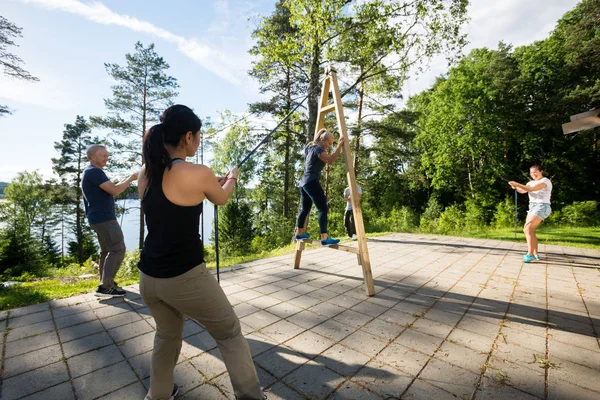 Amis tirant des cordes pour équilibrer la femme sur la structure en bois — Photo