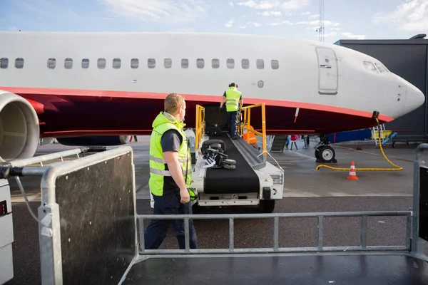 Πλήρωμα που εργάζεται σε μεταφορική αποσκευών που επισυνάπτεται στο αεροπλάνο — Φωτογραφία Αρχείου