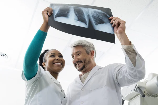 Lächelnde Ärztinnen und Ärzte untersuchen Brust-Röntgen im Krankenhaus — Stockfoto