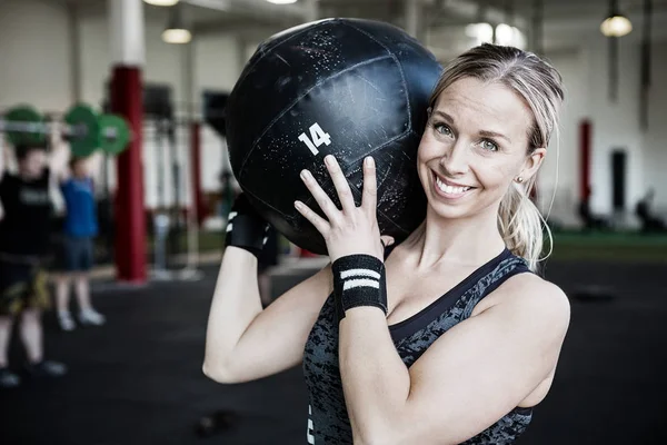 Lächelnde junge Frau hebt Medizinball — Stockfoto
