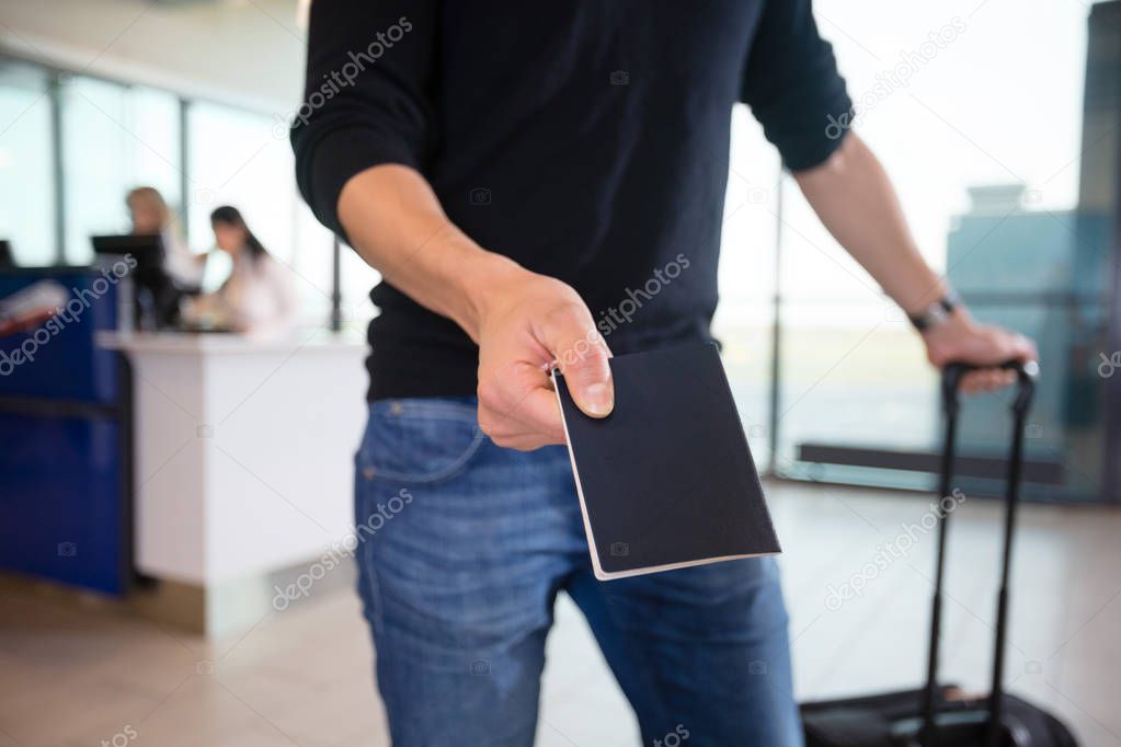 Midsection Of Male Passenger Showing Passport At Airport