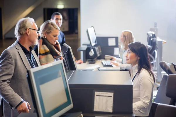 Personál při pohledu na Citi pár na letištní Check-in přepážce — Stock fotografie