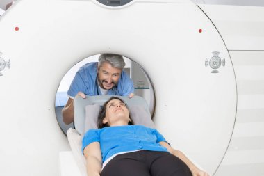 Doctor Preparing Patient For CT Scan In Hospital