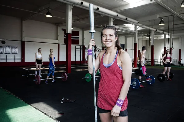 Mujer feliz sosteniendo barra poste en el gimnasio —  Fotos de Stock