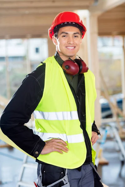 Charpentier debout avec les mains sur les hanches sur le chantier de construction — Photo