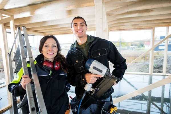 Male And Female Carpenters With Tools Standing At Site — Stock Photo, Image