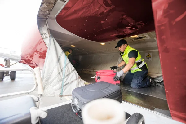 Trabalhador se ajoelhando enquanto descarrega avião — Fotografia de Stock