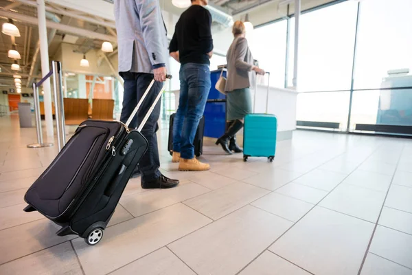 Пассажиры, стоящие на этаже с багажом на стойке регистрации аэропорта А — стоковое фото