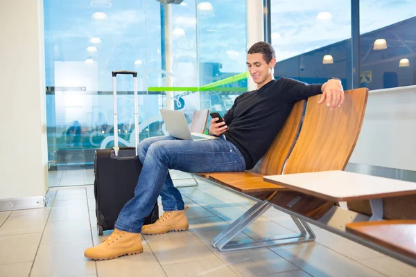 Человек, использующий мобильный телефон в зоне ожидания аэропорта — стоковое фото