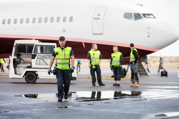 Självsäker arbetare i promenader medan kollegor står på våta springa — Stockfoto