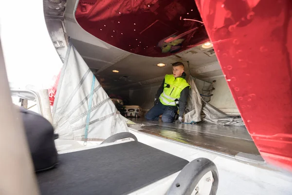 Erkek işçi uçağın içinde diz çökmüş