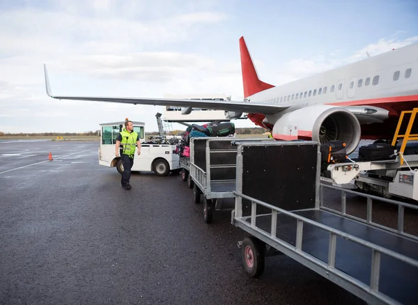 Werknemer wandelen door bagage aanhangwagens op baan — Stockfoto