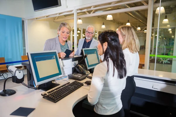 Affärskvinna talar med kvinnlig personal på flygplats incheckning — Stockfoto