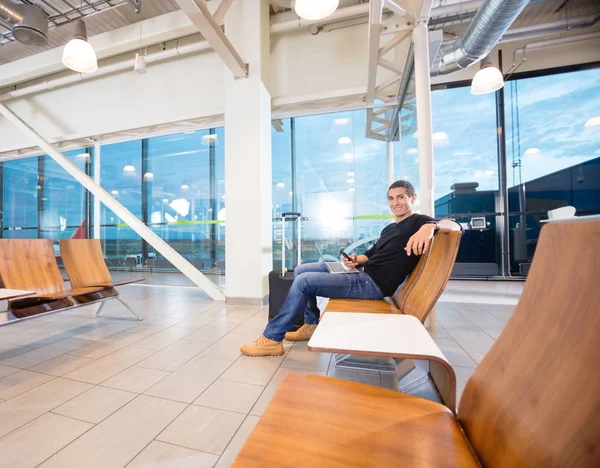 Fiatal ember, mozgatható telefon és Laptop repülőtéren — Stock Fotó