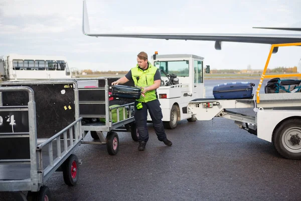 Arbeiter stellt Gepäck in Anhänger auf Landebahn — Stockfoto