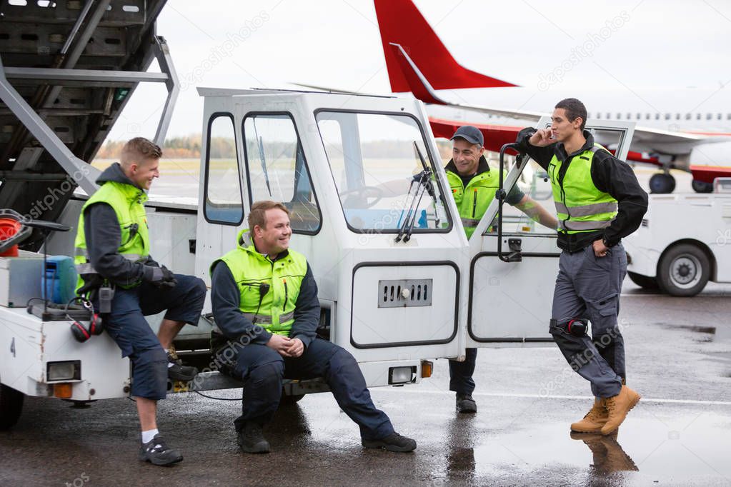 Male Workers Communicating At Gangway On Wet Runway