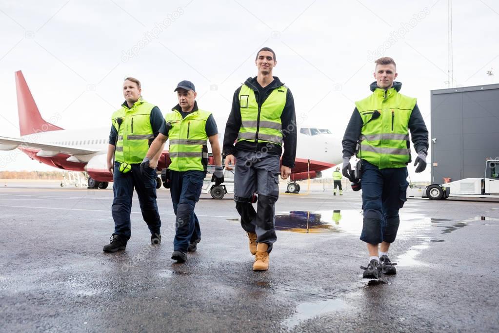 Full Length Of Workers Walking On Wet Runway