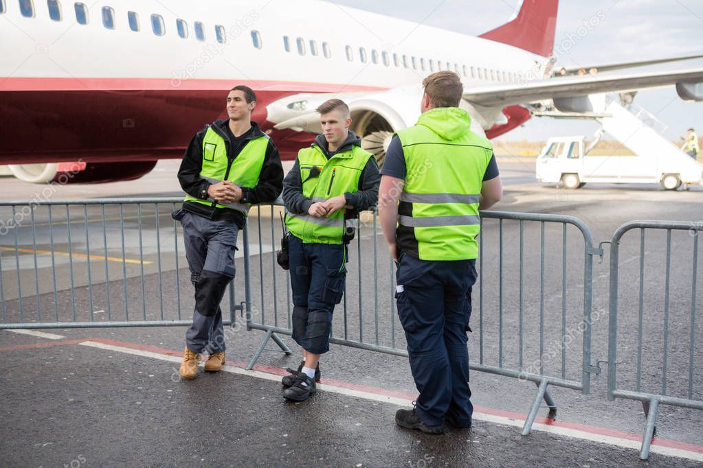 Crew Members Standing By Fence Against Airplane