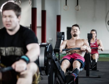 Spor salonunda kürek makine kolu çekerek adam