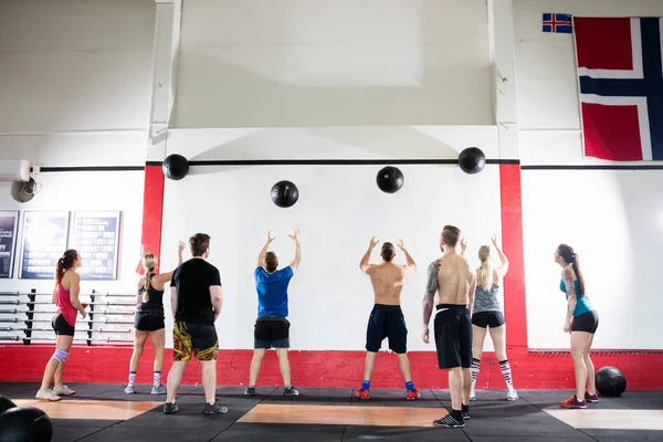 Klienter som kastar medicinbollar på väggen i gymmet — Stockfoto