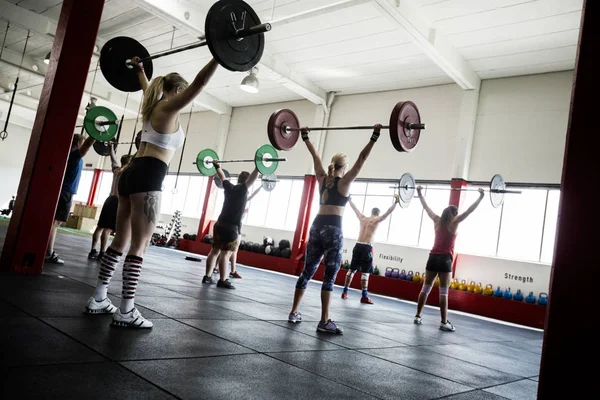 Atleti maschi e femmine che sollevano bilancieri — Foto Stock