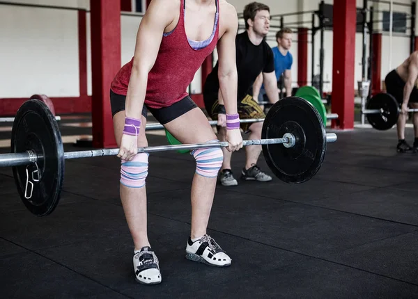 Baixa seção de fêmea instrutor de elevação Barbell — Fotografia de Stock