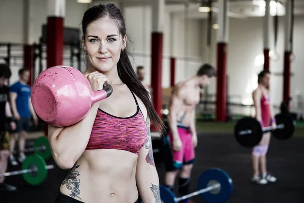 Mladá žena zvedání kettlebell v tělocvičně — Stock fotografie