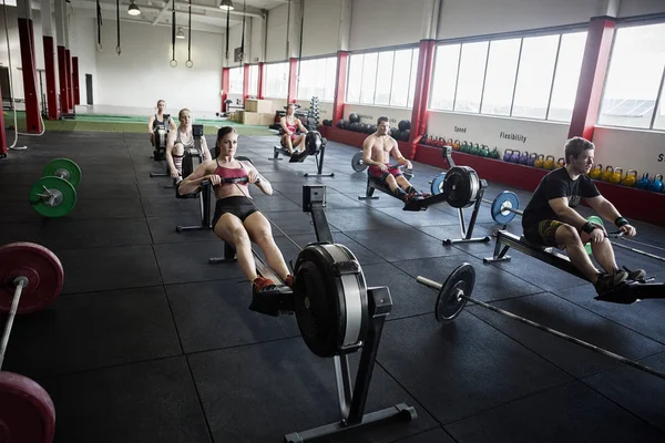 Klienter som använder roddmaskiner i gymmet — Stockfoto