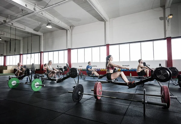 Kadın ve erkek sporcular kürek makine kullanarak — Stok fotoğraf