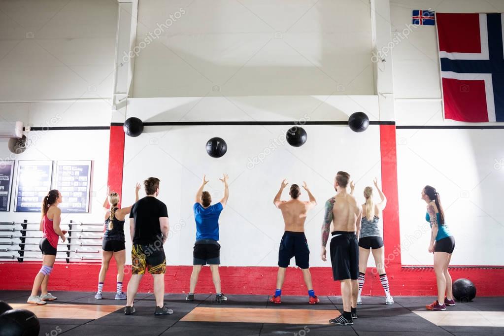Clients Throwing Medicine Balls On Wall In Gym