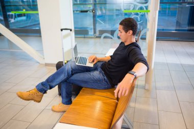 Alan bekleyen havaalanında dizüstü bilgisayar kullanan adam