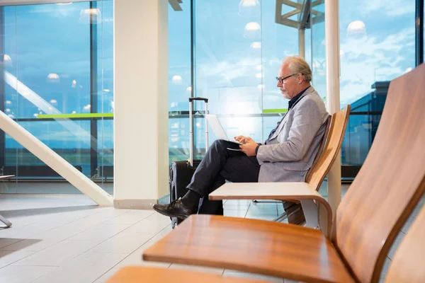 Senior affärsman använder Laptop väntan på flyg — Stockfoto