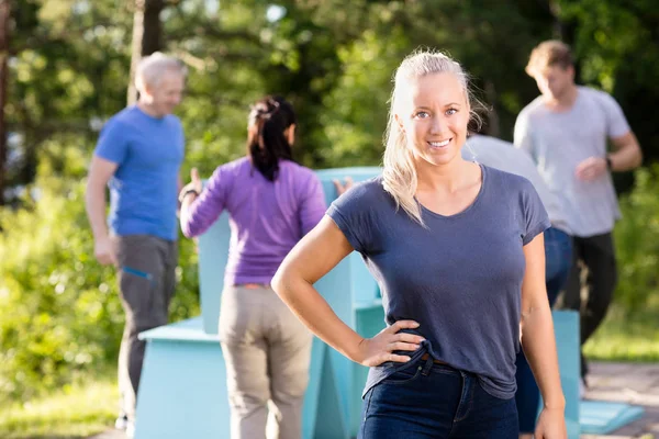 Woman Standing With Hand On Hip While Friends Making Pyramid — Stock Photo, Image