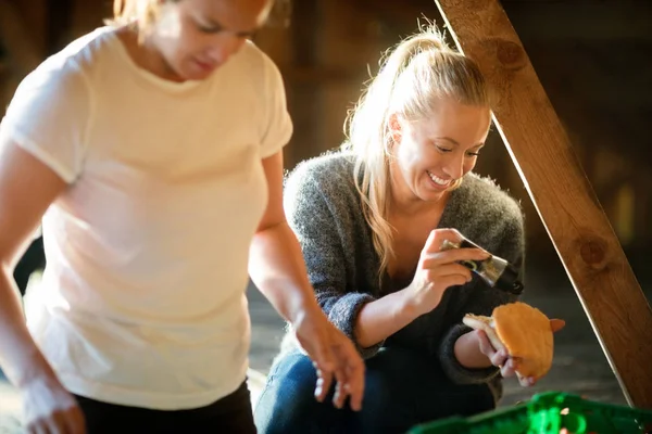 Glimlachend jonge vrouw kruiden brood door collega In bos — Stockfoto