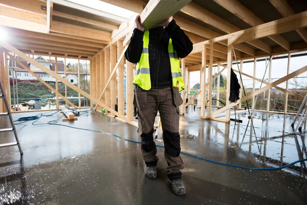 Nízké část mužského Carpenter nesoucí dřevěné prkno — Stock fotografie