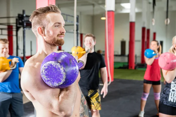 Manlig instruktör lyft Kettlebell med klienter i gymmet — Stockfoto