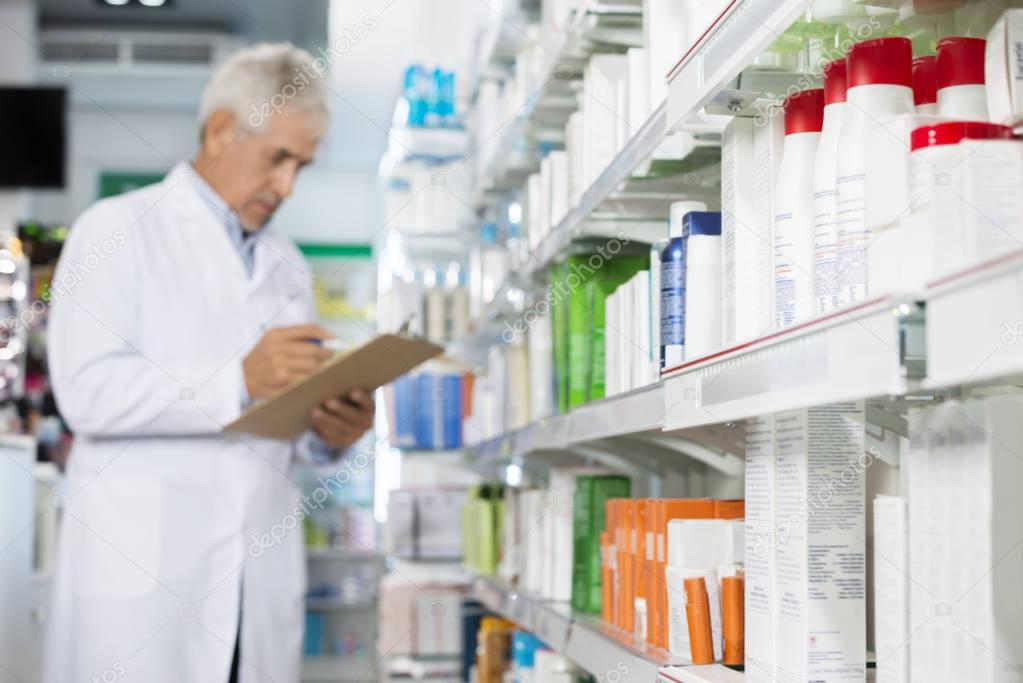 Pharmacist Holding Clipboard While Counting Stock