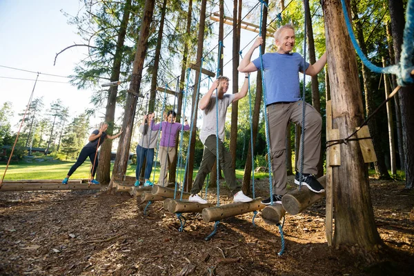 Coworkers Crossing Swinging Logs In Forest — Stock Photo, Image