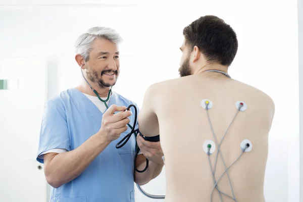 Médico examinando paciente com eletrodos anexados nas costas — Fotografia de Stock